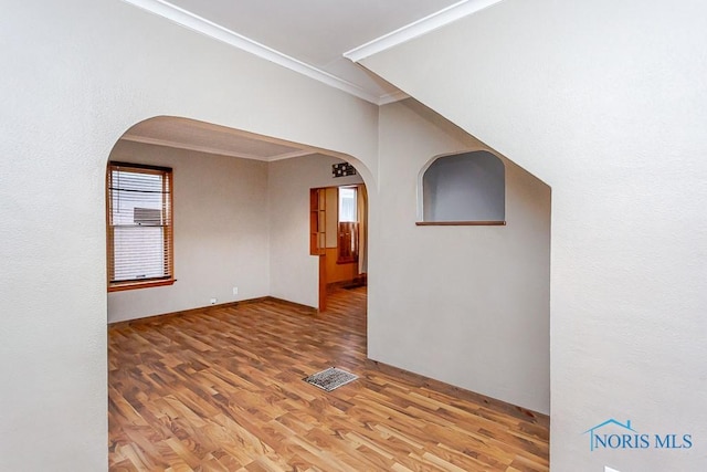 spare room with crown molding and wood-type flooring