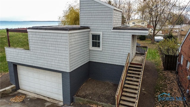 view of side of property with a garage and a water view