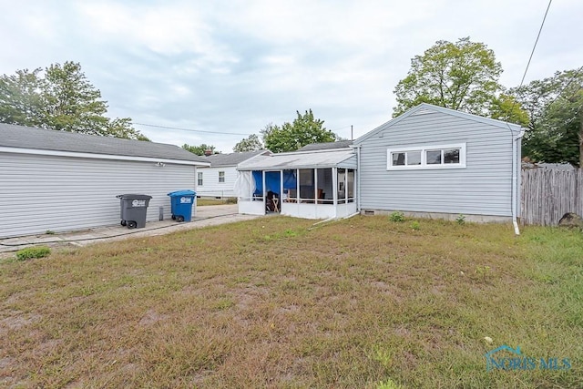 rear view of house featuring a lawn and a sunroom