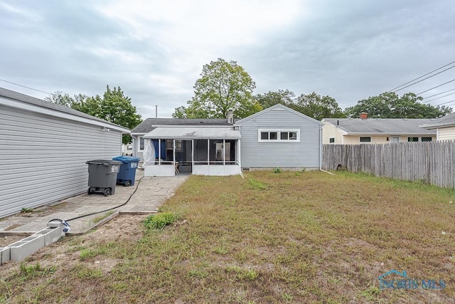 rear view of house with a sunroom and a yard