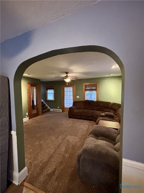 living room with a textured ceiling, carpet floors, and ceiling fan