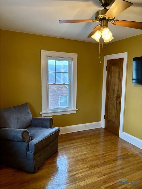 sitting room with ceiling fan and wood-type flooring