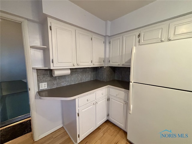 kitchen with white cabinets, white refrigerator, light hardwood / wood-style floors, and tasteful backsplash