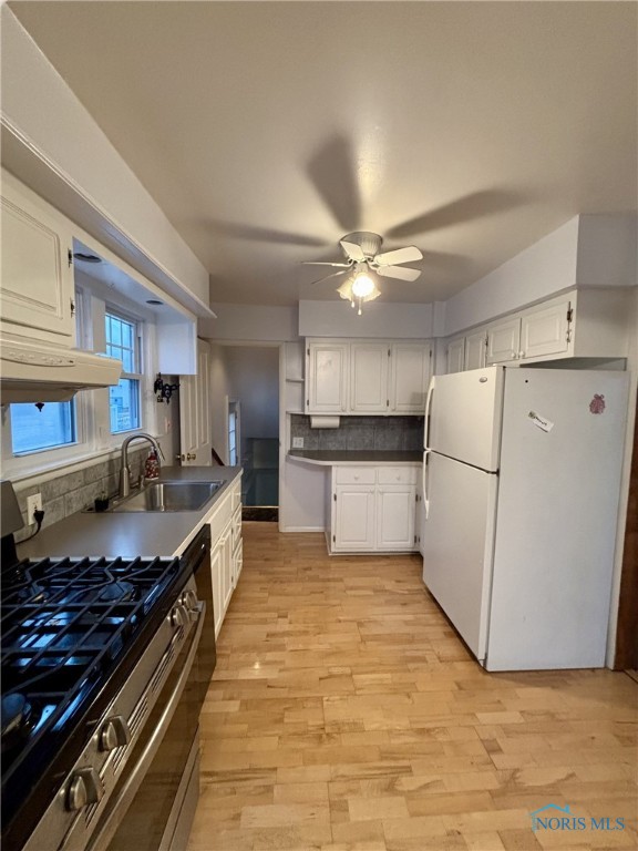 kitchen with decorative backsplash, gas range, sink, white refrigerator, and white cabinets