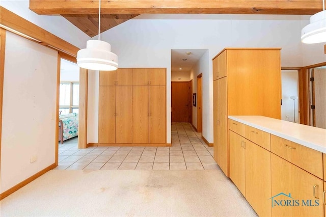 kitchen with beam ceiling, light carpet, and hanging light fixtures