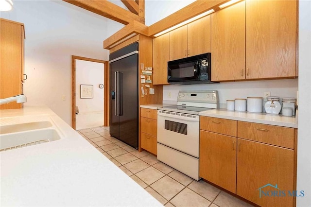 kitchen featuring built in refrigerator, sink, light tile patterned floors, and range