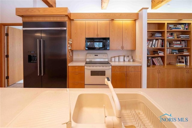 kitchen featuring beam ceiling, stainless steel built in refrigerator, and range