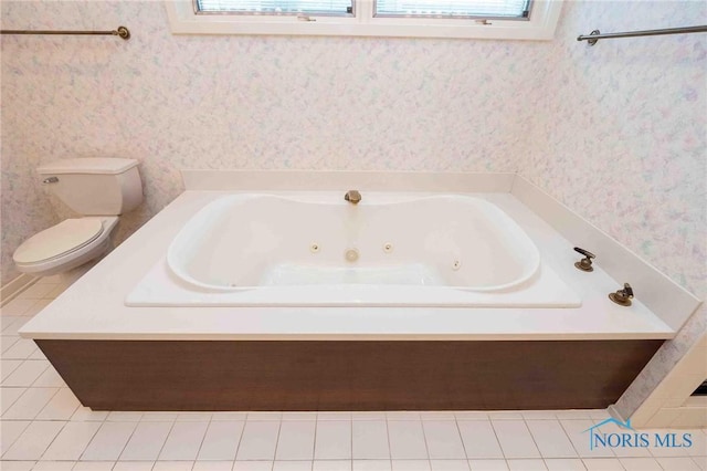 bathroom featuring tile patterned floors, a tub to relax in, and toilet