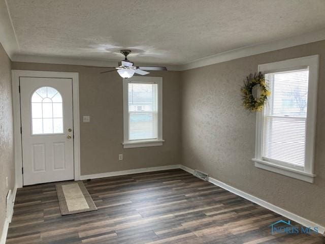 foyer entrance featuring ornamental molding, a textured ceiling, ceiling fan, and dark wood-type flooring