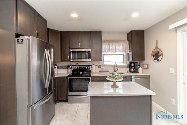 kitchen featuring a center island, sink, stainless steel appliances, dark brown cabinets, and light tile patterned floors