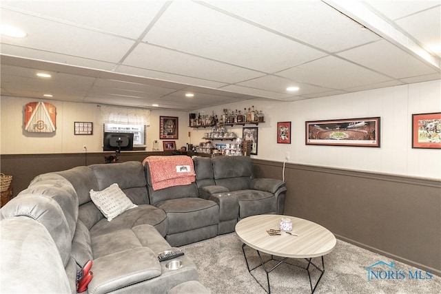 living room with bar, a paneled ceiling, and carpet flooring