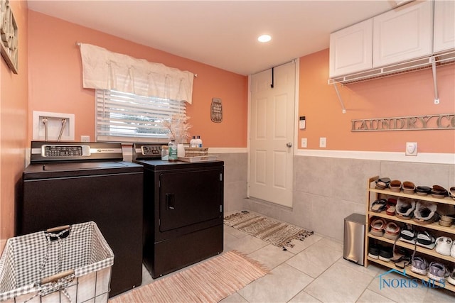 laundry room featuring washer and clothes dryer, light tile patterned flooring, cabinets, and tile walls