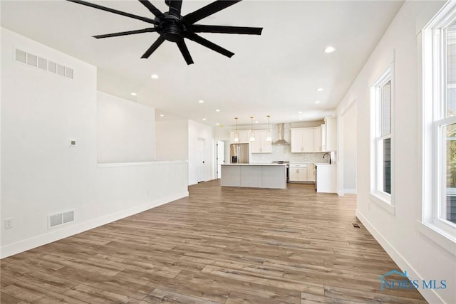 unfurnished living room featuring ceiling fan, sink, and hardwood / wood-style flooring