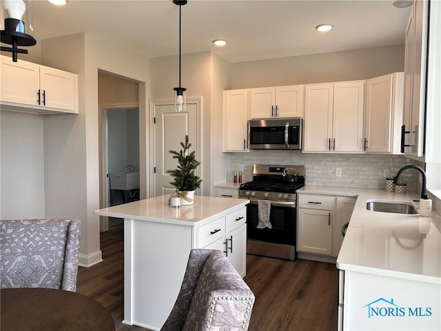 kitchen featuring pendant lighting, sink, appliances with stainless steel finishes, white cabinets, and a kitchen island