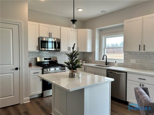 kitchen with stainless steel appliances, sink, a kitchen island, and white cabinets