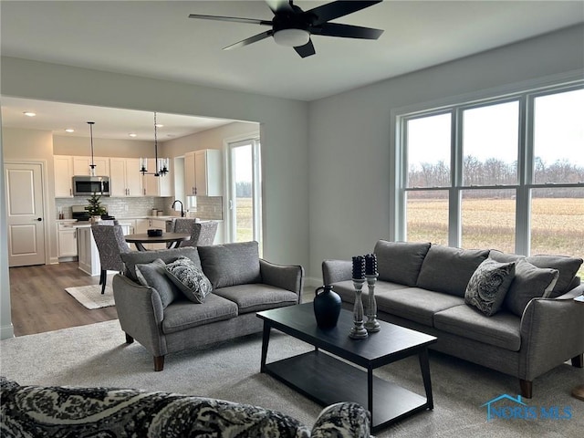 living room featuring sink, light hardwood / wood-style floors, and ceiling fan