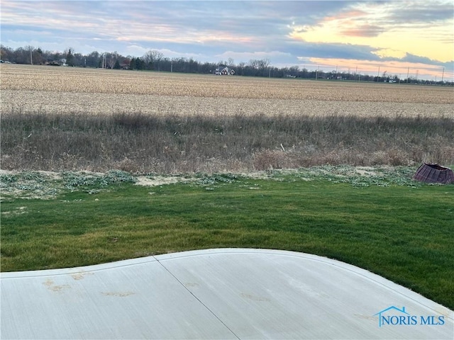 yard at dusk featuring a rural view