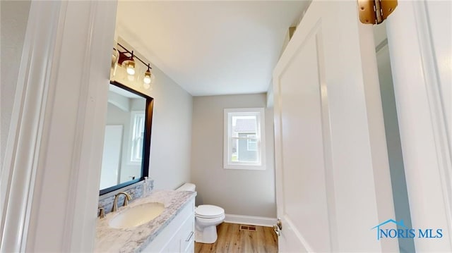 bathroom with vanity, toilet, and hardwood / wood-style flooring