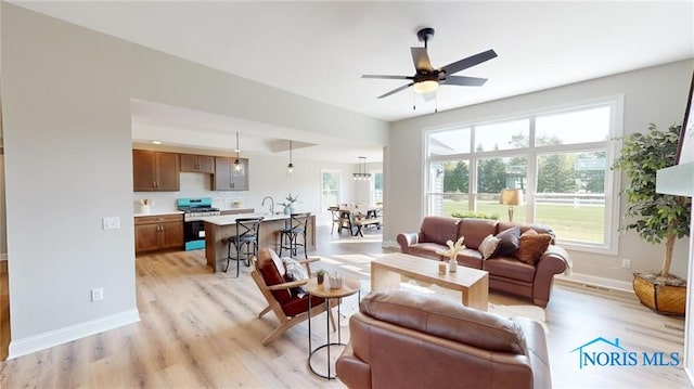 living room featuring sink, light hardwood / wood-style flooring, and ceiling fan