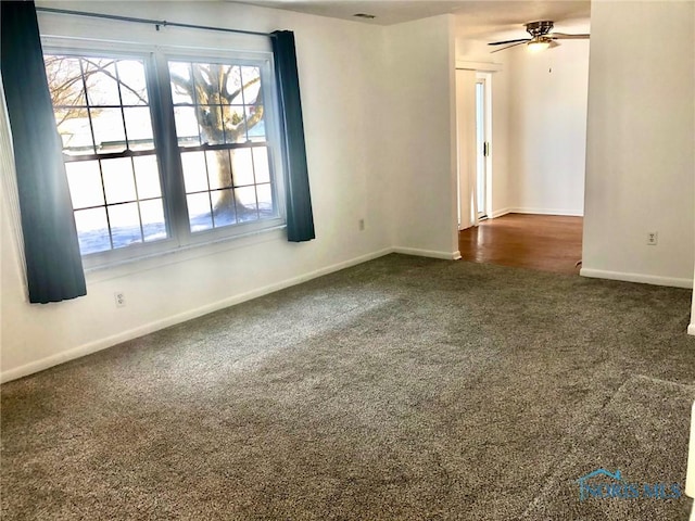 spare room featuring ceiling fan and dark carpet