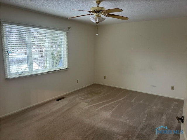 unfurnished room with ceiling fan, a textured ceiling, and dark colored carpet