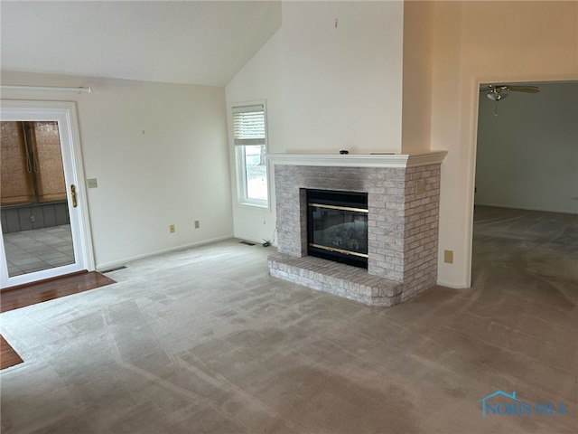 unfurnished living room with carpet, a brick fireplace, vaulted ceiling, and ceiling fan