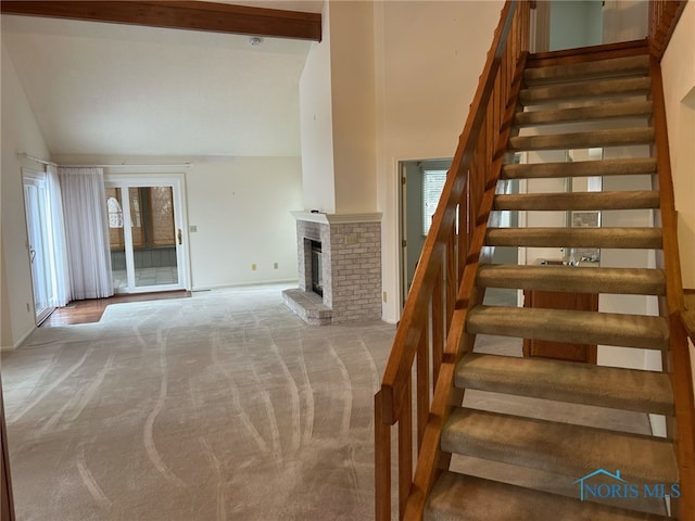 stairway featuring carpet flooring, high vaulted ceiling, and a brick fireplace