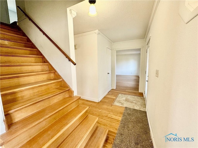 staircase featuring hardwood / wood-style floors and ornamental molding