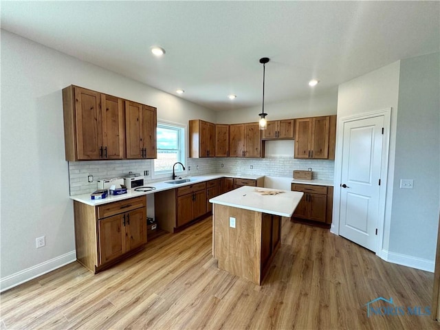 kitchen with sink, a center island, pendant lighting, light hardwood / wood-style floors, and a breakfast bar