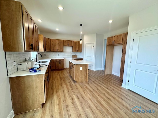 kitchen featuring decorative backsplash, sink, decorative light fixtures, light hardwood / wood-style floors, and a kitchen island