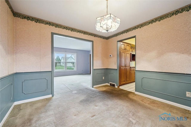 carpeted spare room with an inviting chandelier