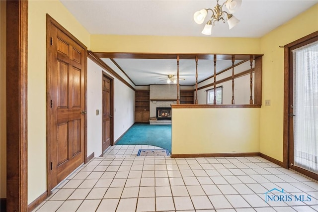 kitchen featuring a brick fireplace, ornamental molding, ceiling fan with notable chandelier, light colored carpet, and a healthy amount of sunlight