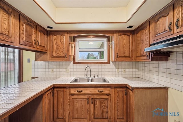 kitchen with backsplash, tile counters, and sink