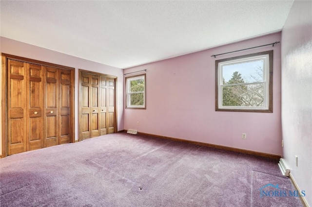 unfurnished bedroom featuring carpet floors and two closets