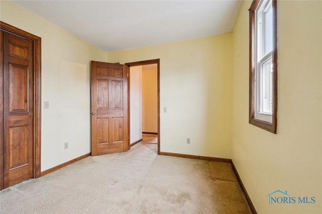 unfurnished bedroom featuring light carpet and multiple windows