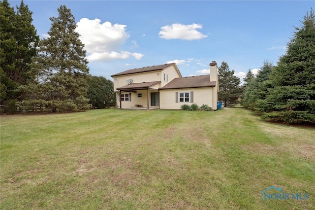 rear view of property featuring a lawn