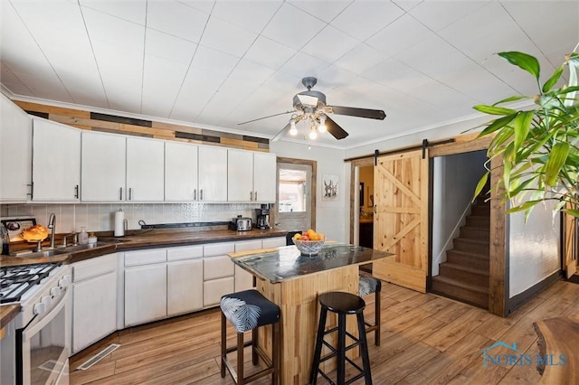 kitchen with white cabinetry, a breakfast bar, a barn door, and a center island