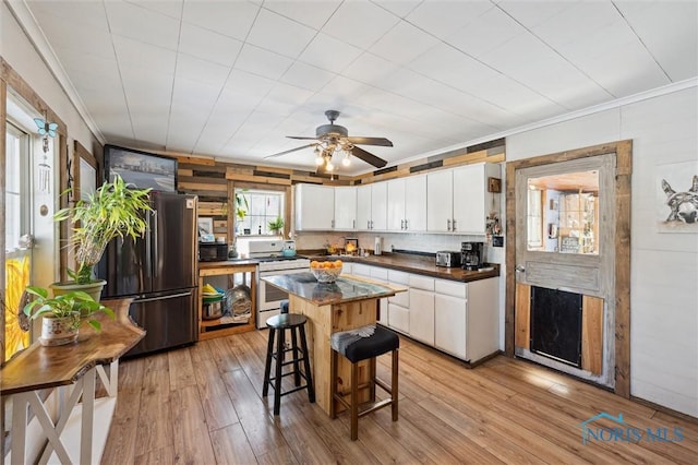 kitchen featuring white cabinets, a center island, light hardwood / wood-style floors, black appliances, and a breakfast bar