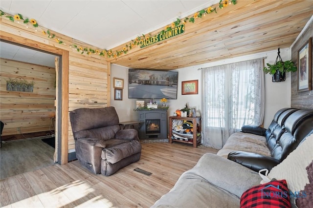 living room with hardwood / wood-style flooring, wood walls, and a fireplace