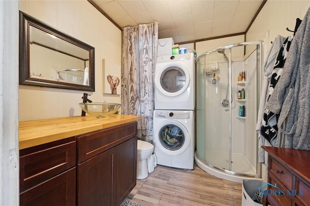 washroom with sink, light hardwood / wood-style flooring, stacked washer / drying machine, and ornamental molding