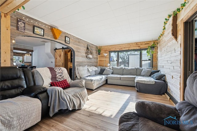 living room featuring a wealth of natural light, a barn door, wood walls, and wood-type flooring