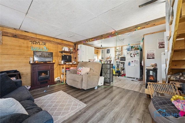 living room with hardwood / wood-style floors, wooden walls, and a fireplace