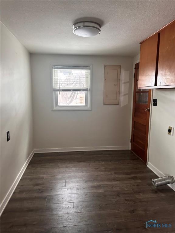 unfurnished room with a textured ceiling, electric panel, and dark hardwood / wood-style floors