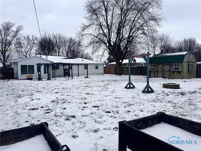 yard layered in snow with an outbuilding and an outdoor fire pit