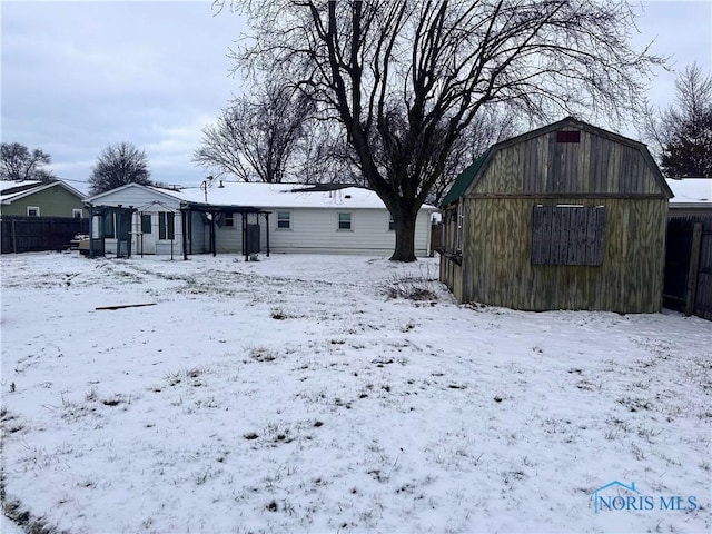 snow covered back of property with an outbuilding