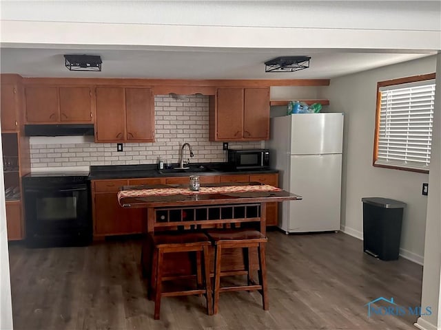 kitchen with tasteful backsplash, dark hardwood / wood-style flooring, sink, and black appliances