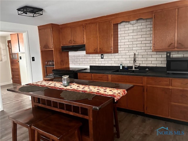 kitchen featuring tasteful backsplash, sink, black electric range oven, and dark wood-type flooring