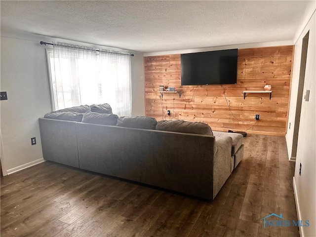 living room with hardwood / wood-style floors, wood walls, and a textured ceiling