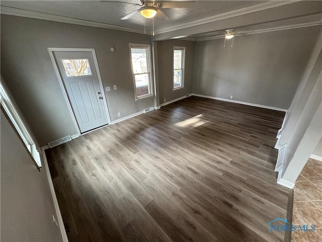 entrance foyer with a healthy amount of sunlight, dark hardwood / wood-style flooring, and ornamental molding