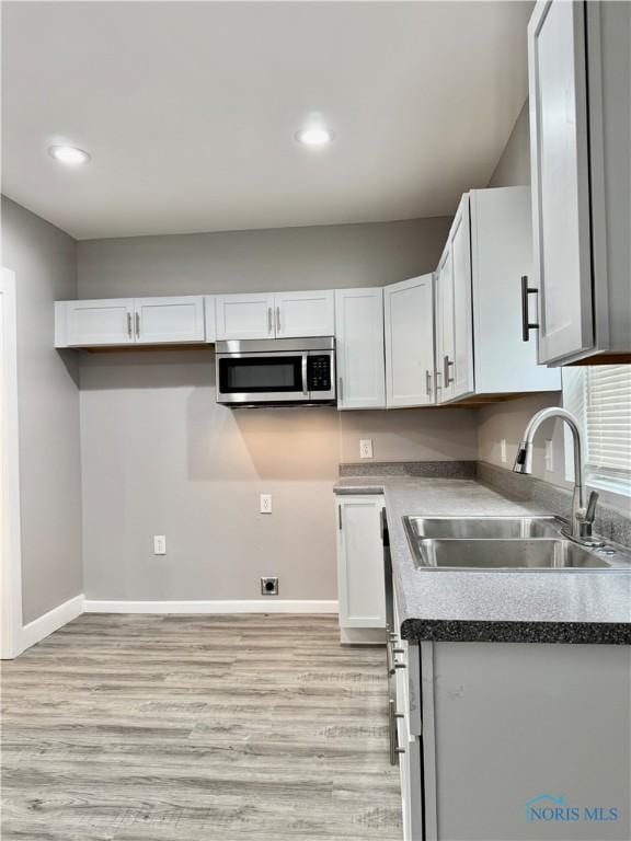 kitchen featuring light wood-type flooring, sink, and white cabinetry